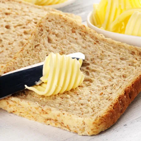knife spreading butter on slice of bread