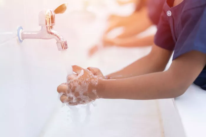Students at school washing hands with soap under the faucet with water