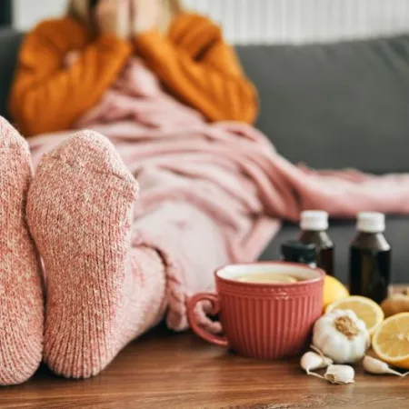 Feet wearing warm socks on a low table beside cold medicine and home remedies